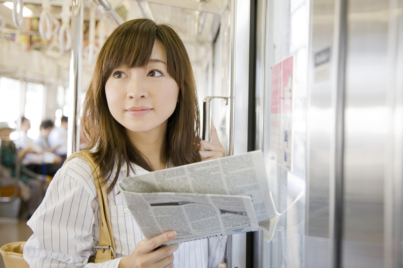 朝の電車通勤で新聞を読む